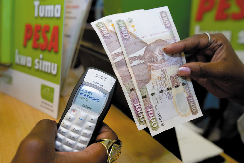 A money transfer in progress on a Nokia 1100 handset, Kenyan shilling notes held beside it