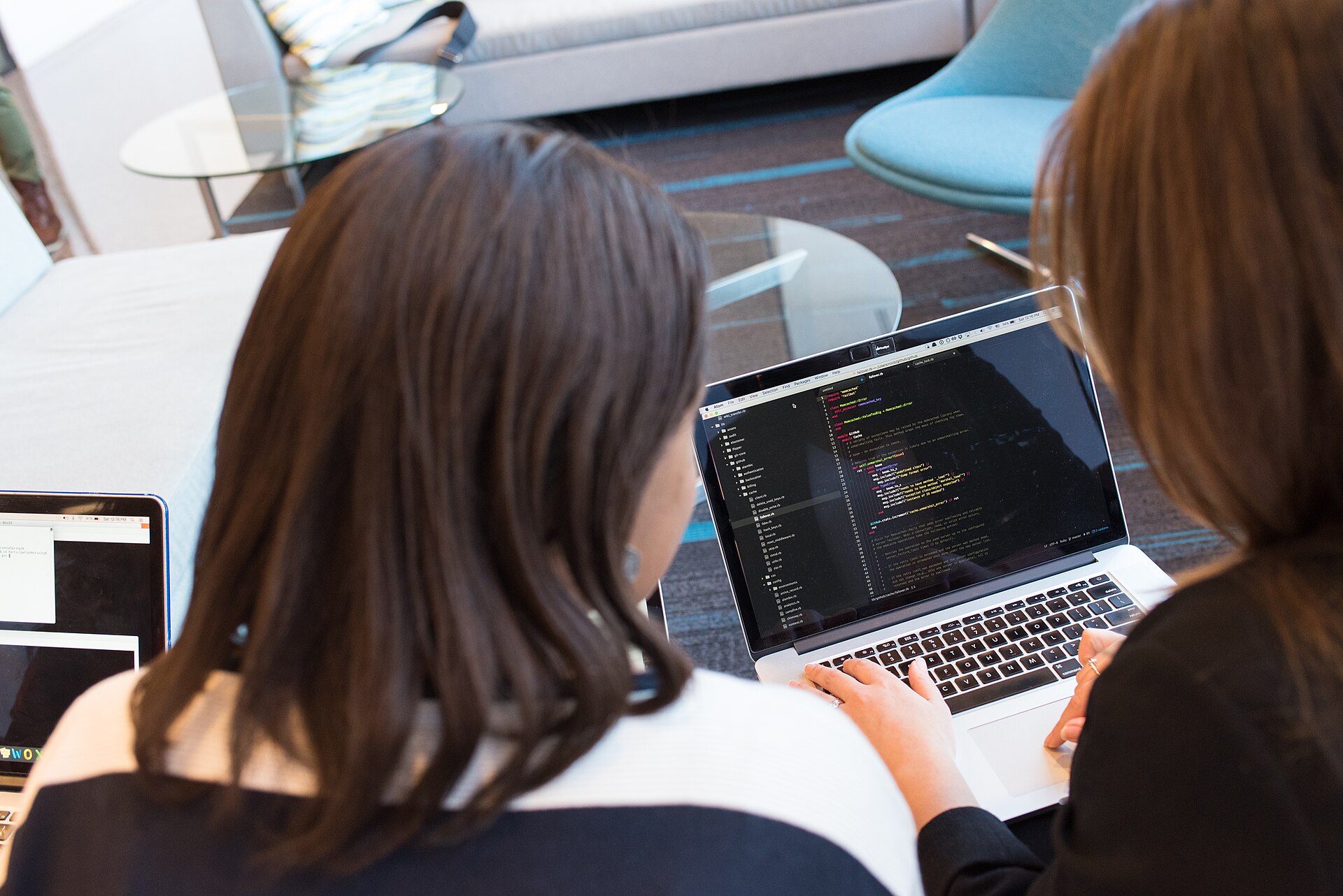 Two engineers working through code together on a laptop